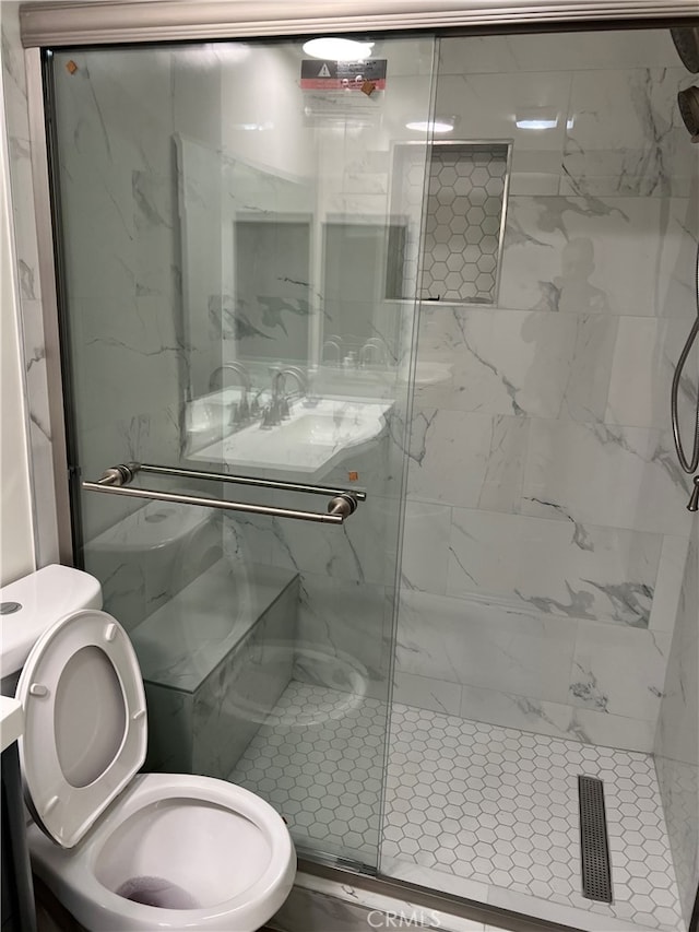 full bathroom featuring a sink, a marble finish shower, and toilet