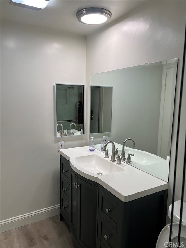 bathroom with baseboards, toilet, wood finished floors, and vanity