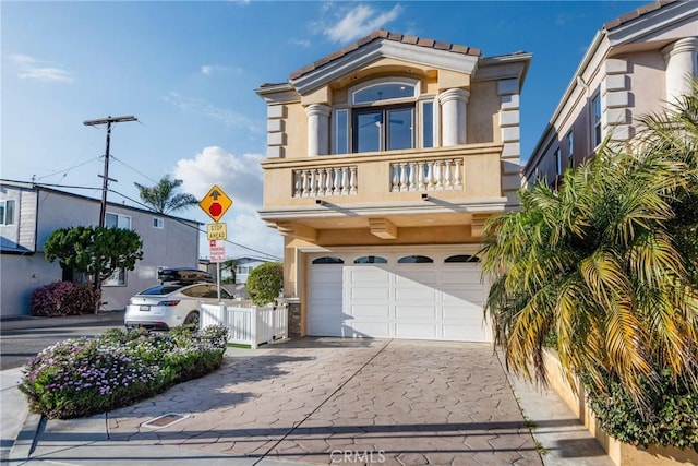 view of front of property featuring fence, concrete driveway, stucco siding, a balcony, and an attached garage