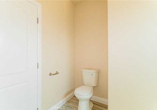 bathroom featuring toilet, baseboards, and wood finished floors