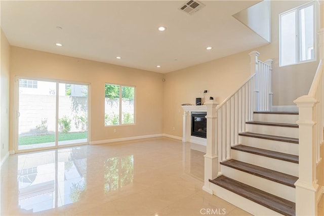 living area with a glass covered fireplace, stairway, recessed lighting, and visible vents