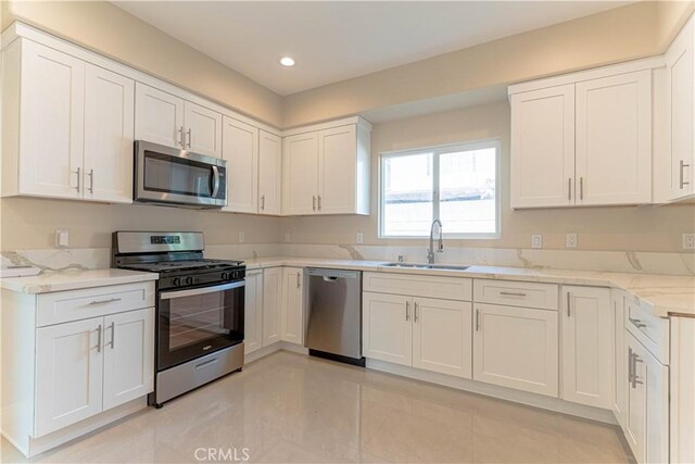 kitchen featuring a sink, white cabinetry, recessed lighting, appliances with stainless steel finishes, and light stone countertops