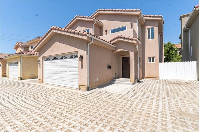 view of front of home featuring a tiled roof, an attached garage, fence, and stucco siding