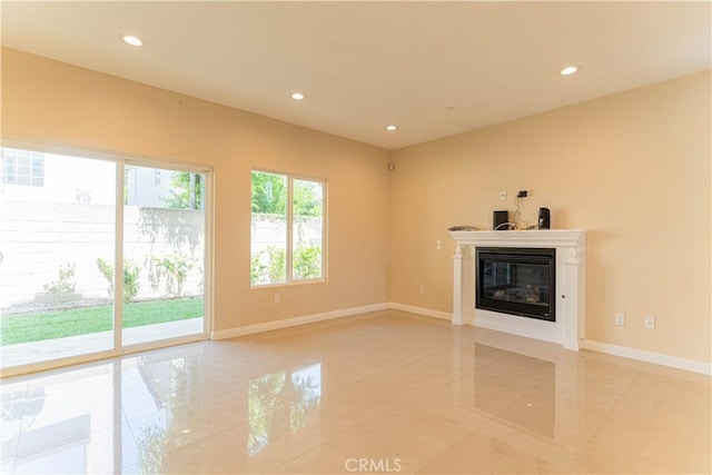 unfurnished living room featuring a glass covered fireplace, recessed lighting, baseboards, and marble finish floor