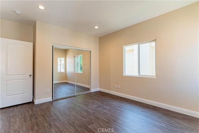 unfurnished bedroom with recessed lighting, a closet, baseboards, and dark wood-style flooring