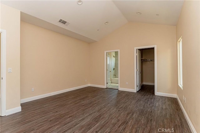 unfurnished bedroom with visible vents, baseboards, dark wood-style flooring, vaulted ceiling, and a walk in closet