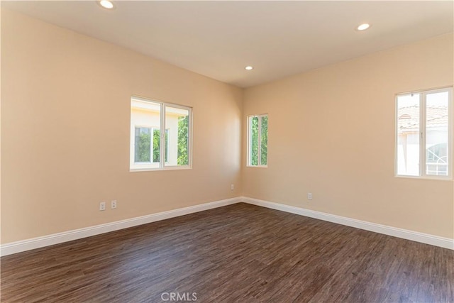 spare room featuring dark wood finished floors, recessed lighting, and baseboards