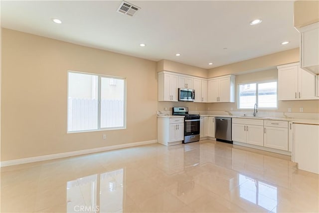 kitchen featuring visible vents, baseboards, light countertops, stainless steel appliances, and a sink