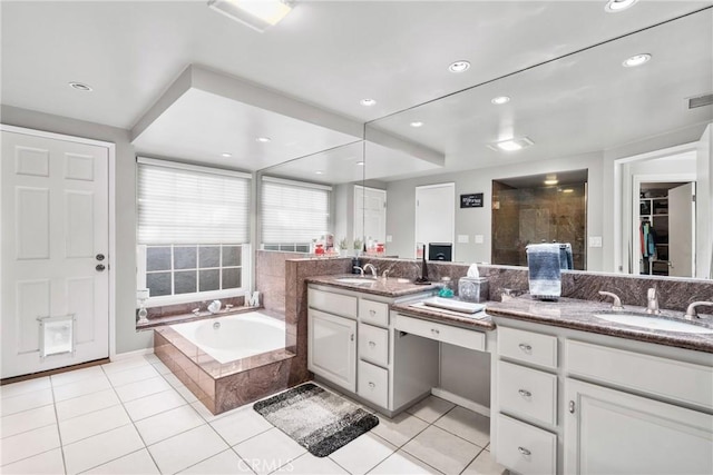 bathroom with double vanity, a bath, tile patterned floors, and a sink