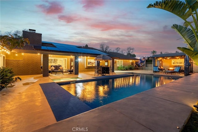 pool at dusk with outdoor dining space, a patio, an outdoor pool, and an outdoor living space