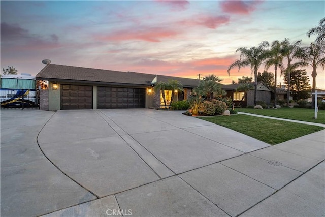 view of front of property featuring driveway, a lawn, an attached garage, and fence