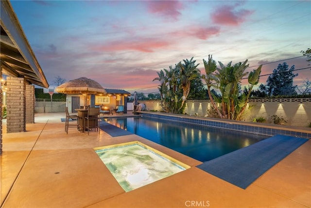 view of pool featuring a fenced in pool, a fenced backyard, an outdoor structure, a patio area, and an in ground hot tub