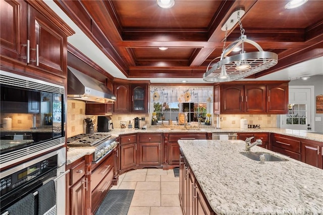 kitchen featuring stainless steel gas cooktop, decorative backsplash, coffered ceiling, wall chimney exhaust hood, and a sink