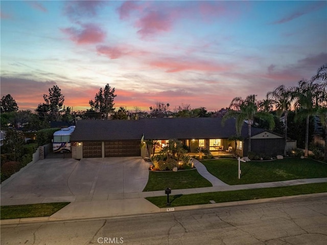 ranch-style home featuring a garage, concrete driveway, and a front yard