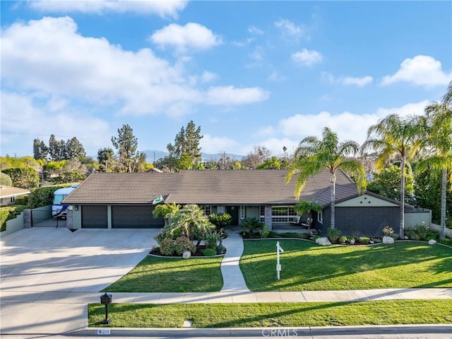 ranch-style home with fence, a tile roof, a front yard, a garage, and driveway