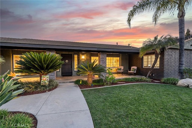 mid-century home with stone siding and a lawn