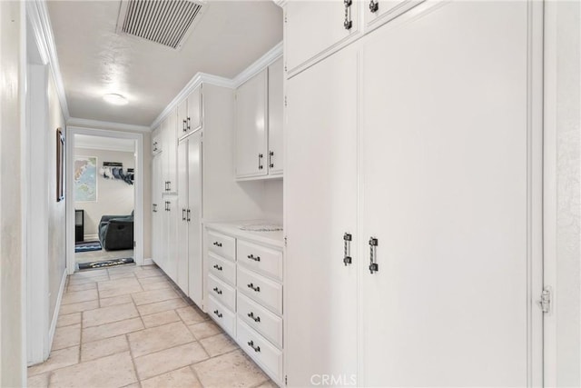 hall featuring crown molding, visible vents, and stone tile flooring