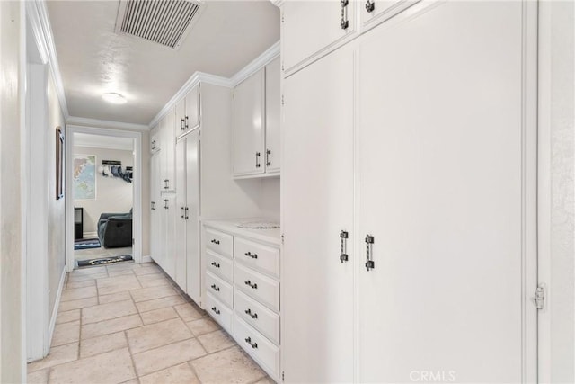 interior space featuring stone tile flooring, baseboards, visible vents, and ornamental molding
