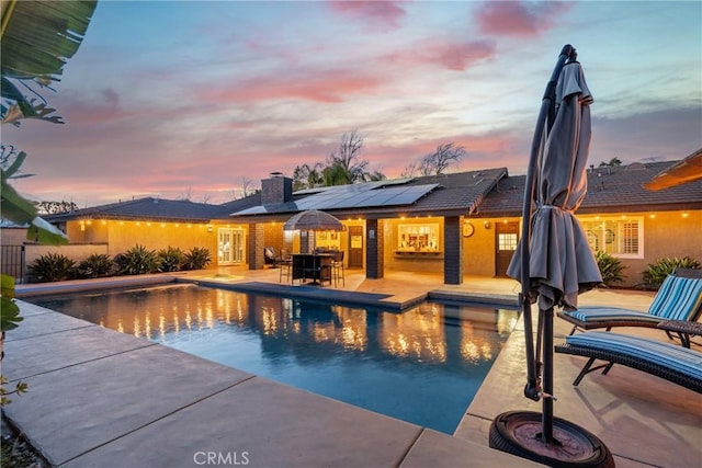 pool at dusk with a fenced in pool and a patio