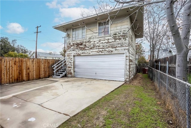 exterior space featuring an attached garage, fence, stairs, a patio area, and driveway