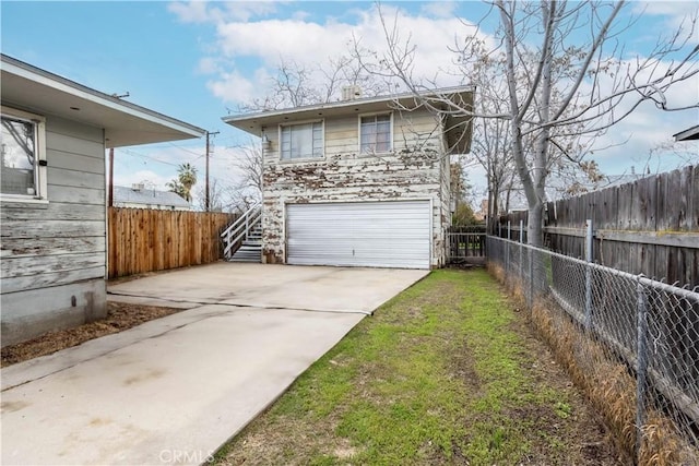 view of side of home featuring an attached garage, driveway, and fence