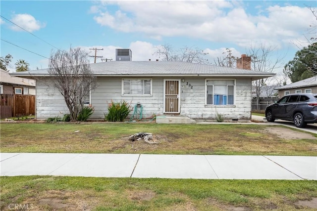 ranch-style home with a front lawn, central AC unit, fence, and a chimney