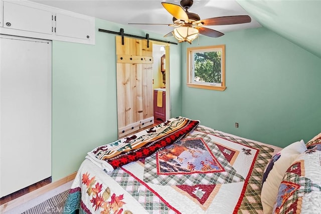 bedroom featuring a barn door, lofted ceiling, and a ceiling fan