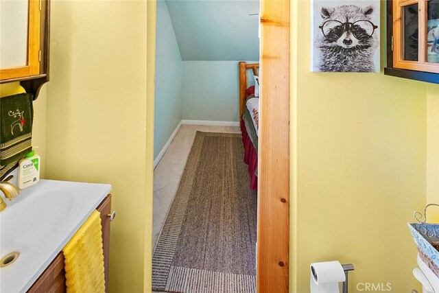 bathroom with vanity, lofted ceiling, and baseboards