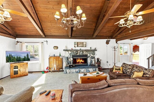 living area with ceiling fan with notable chandelier, a fireplace, vaulted ceiling with beams, and carpet floors