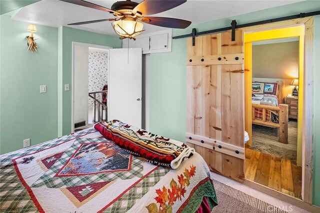 bedroom featuring a barn door, carpet, and ceiling fan