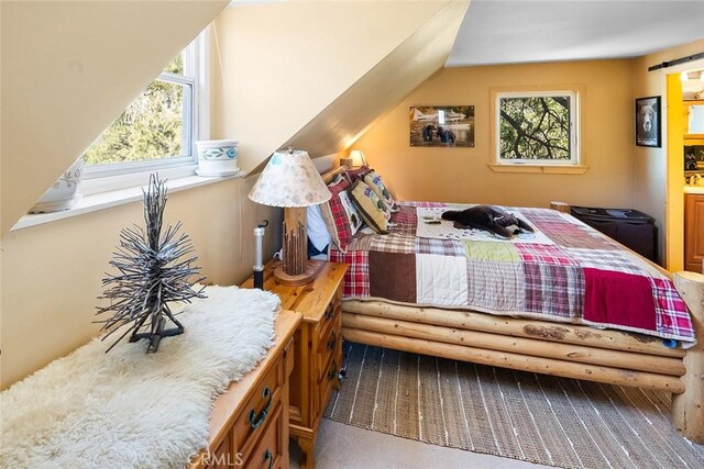 bedroom with multiple windows, carpet, and lofted ceiling