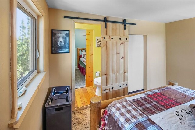 bedroom featuring a barn door and wood finished floors