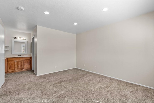 unfurnished bedroom with recessed lighting, light colored carpet, baseboards, and a sink