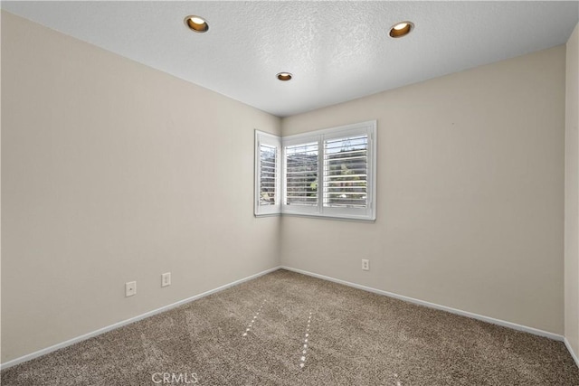 carpeted spare room with recessed lighting, baseboards, and a textured ceiling