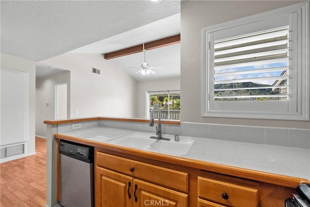 kitchen featuring tile countertops, visible vents, stainless steel dishwasher, and a sink