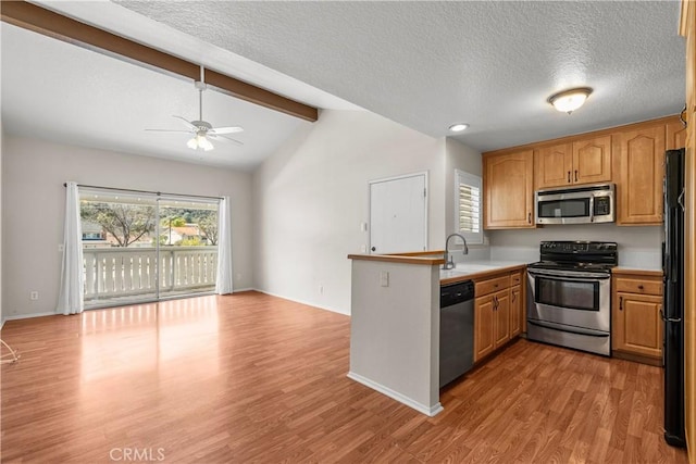 kitchen featuring vaulted ceiling with beams, a peninsula, wood finished floors, stainless steel appliances, and a sink