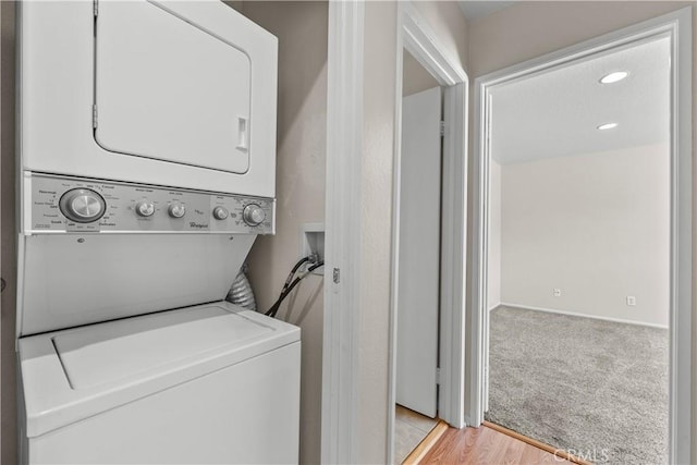 washroom featuring recessed lighting, light wood-style floors, stacked washer / dryer, light colored carpet, and laundry area