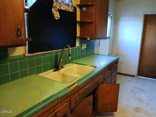 kitchen featuring tile counters, tasteful backsplash, open shelves, and a sink