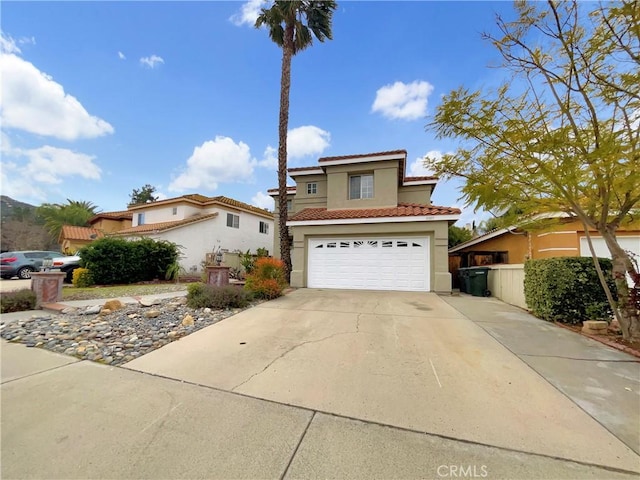 mediterranean / spanish-style home with stucco siding, a tiled roof, concrete driveway, and an attached garage