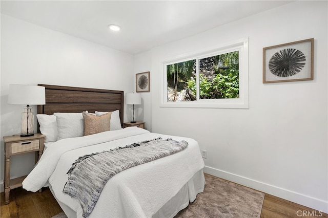 bedroom with recessed lighting, wood finished floors, and baseboards