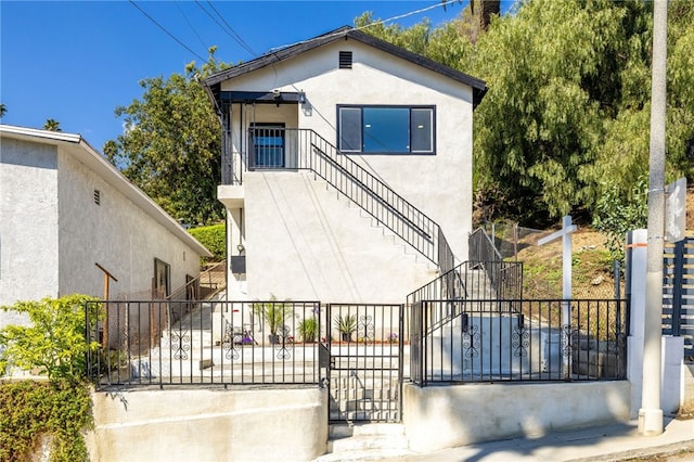 back of house with stairs and stucco siding