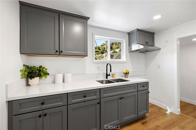 kitchen featuring gray cabinets, light countertops, light wood-type flooring, and a sink