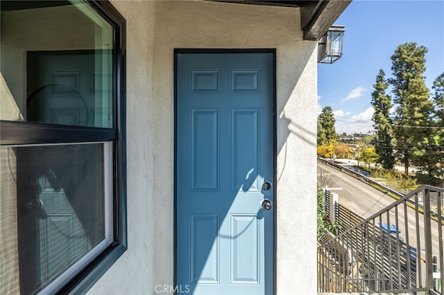 view of exterior entry featuring stucco siding and a balcony