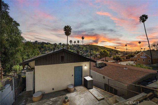 property exterior at dusk with a patio area, stucco siding, and fence