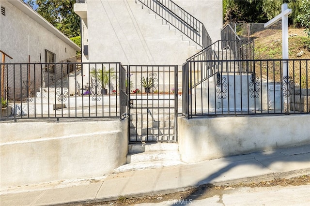 view of gate featuring stairs and fence