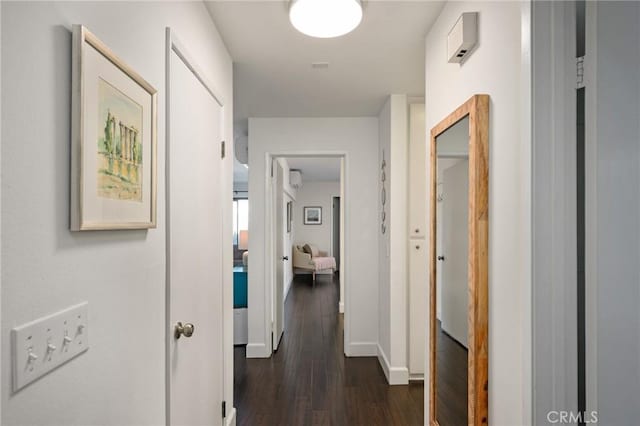 hallway featuring dark wood-type flooring and baseboards