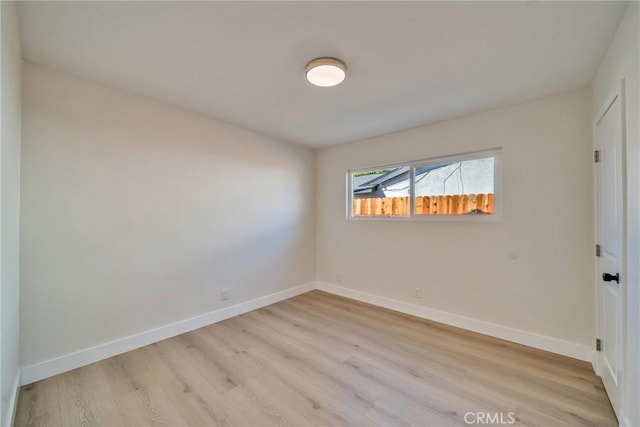 unfurnished room with baseboards and light wood-style floors