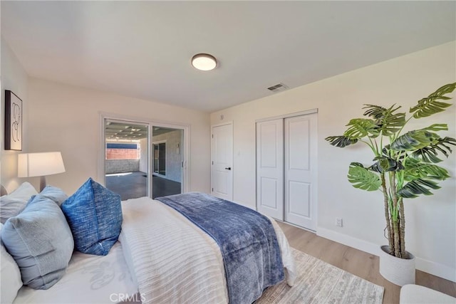 bedroom featuring access to outside, a closet, visible vents, wood finished floors, and baseboards