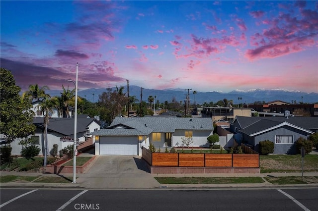 single story home featuring a fenced front yard, a garage, concrete driveway, and a mountain view