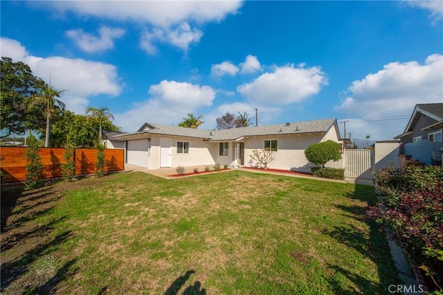 back of property featuring a garage, stucco siding, fence, and a lawn